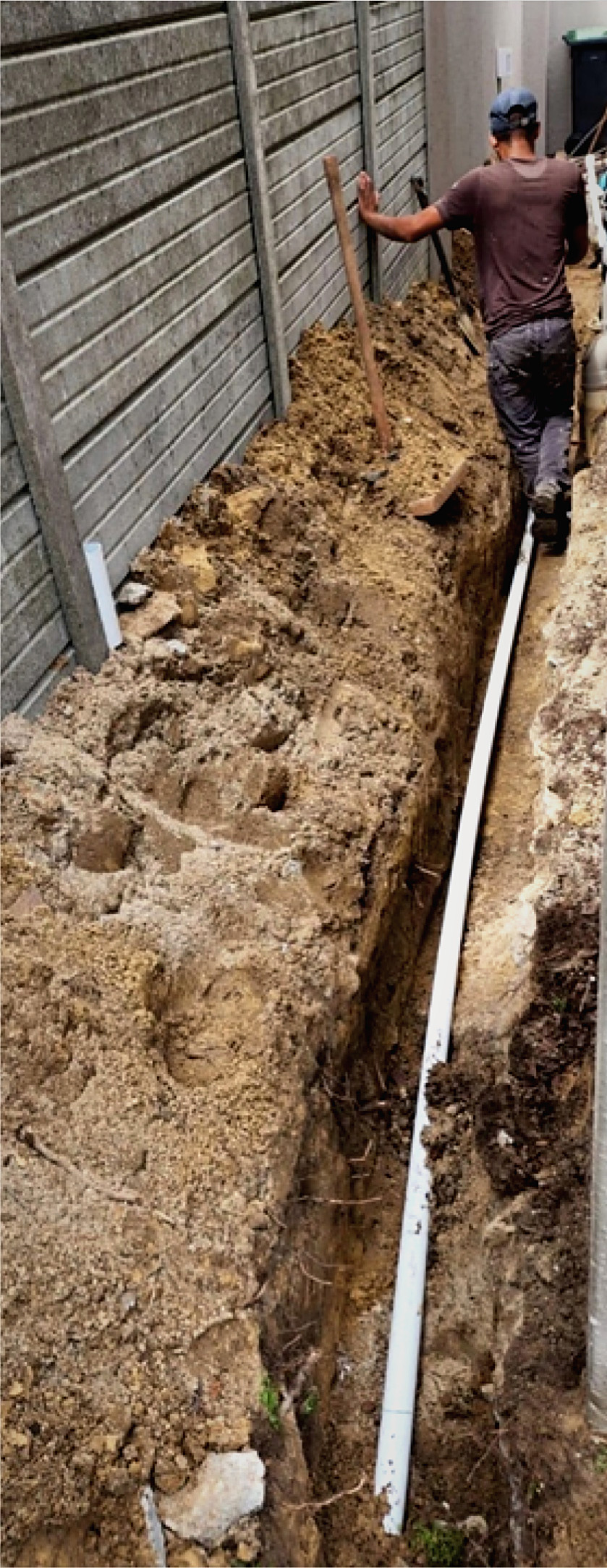 A new water line laid in a trench beside a boundary wall